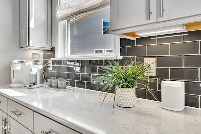 kitchen with white cabinetry, light stone countertops, and decorative backsplash