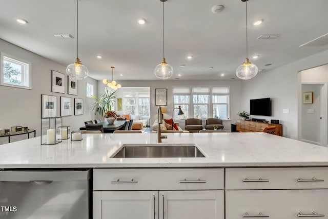 kitchen with sink, white cabinetry, light stone counters, hanging light fixtures, and stainless steel dishwasher