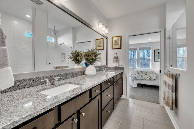 bathroom with tile patterned floors, tiled shower, plenty of natural light, and vanity