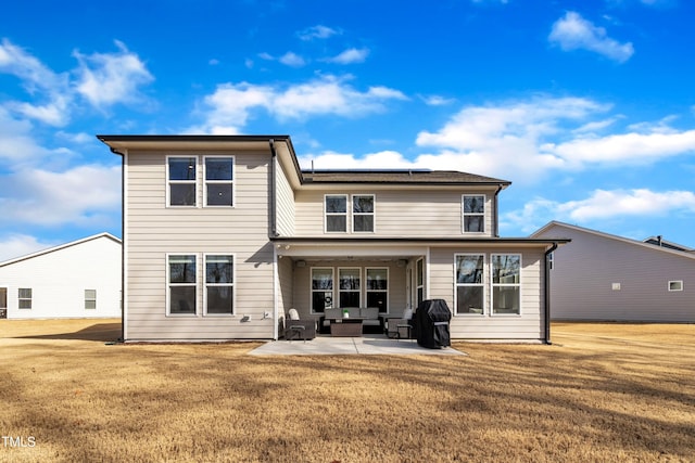 back of property with solar panels, outdoor lounge area, a lawn, and a patio area