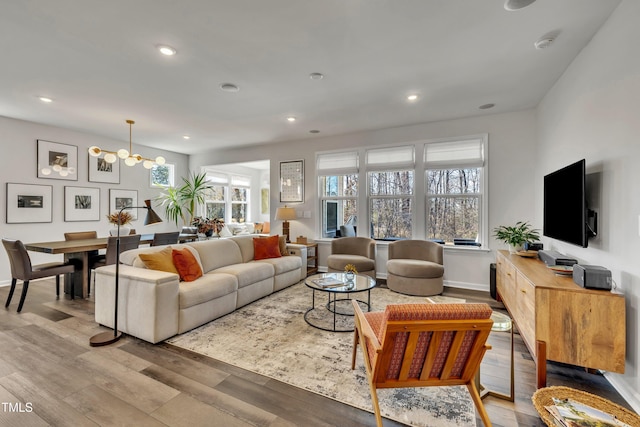 living room with a notable chandelier, light hardwood / wood-style floors, and a healthy amount of sunlight