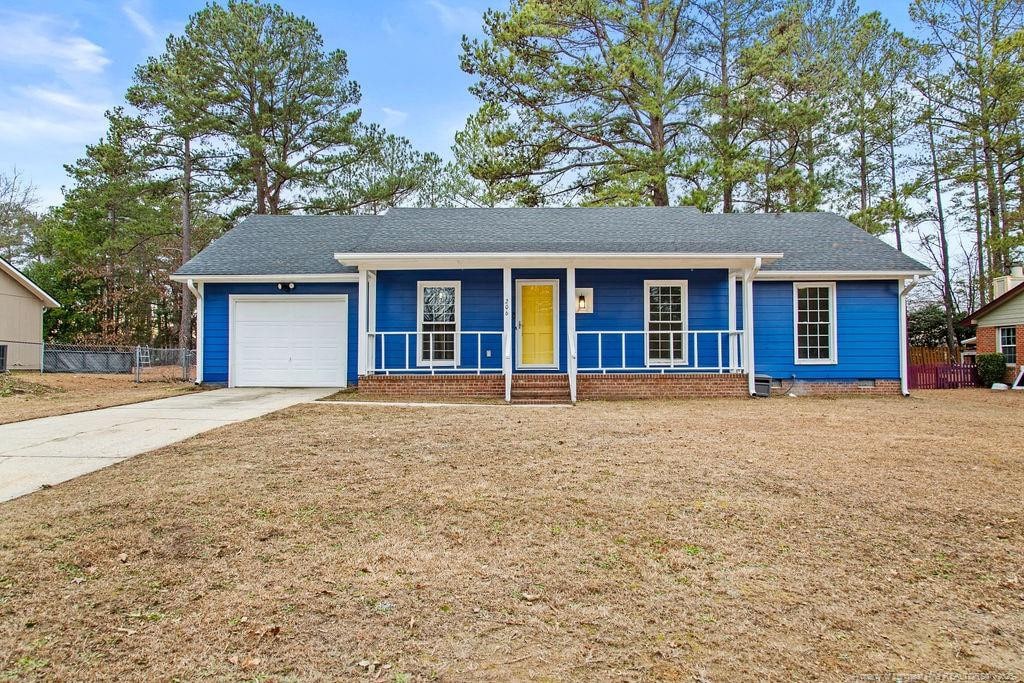 ranch-style home featuring a garage, a front lawn, and covered porch