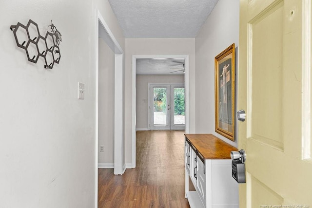 corridor with french doors, dark hardwood / wood-style floors, and a textured ceiling