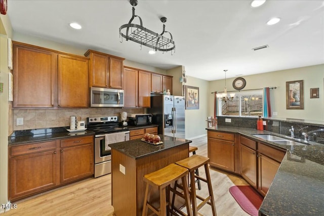 kitchen featuring a kitchen island, decorative light fixtures, sink, a breakfast bar area, and stainless steel appliances