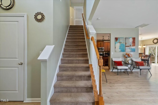 stairs with an inviting chandelier and wood-type flooring