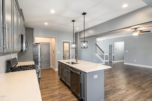 kitchen with appliances with stainless steel finishes, dark hardwood / wood-style floors, pendant lighting, sink, and a kitchen island with sink