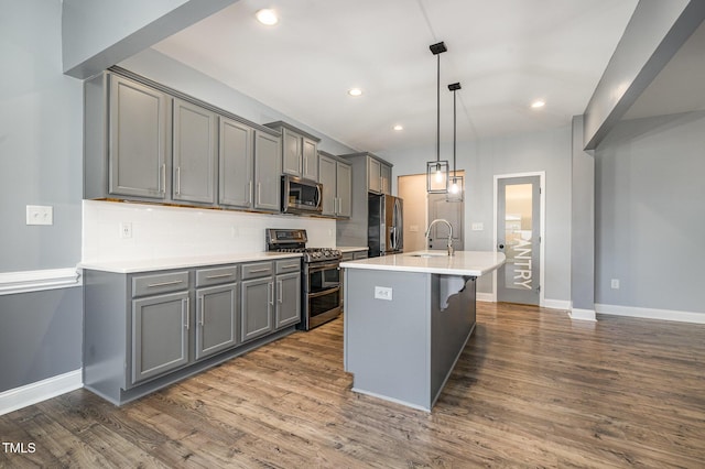 kitchen with pendant lighting, stainless steel appliances, gray cabinets, and sink