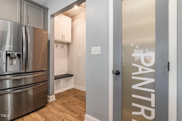 kitchen with stainless steel refrigerator with ice dispenser, gray cabinetry, white cabinets, and light wood-type flooring