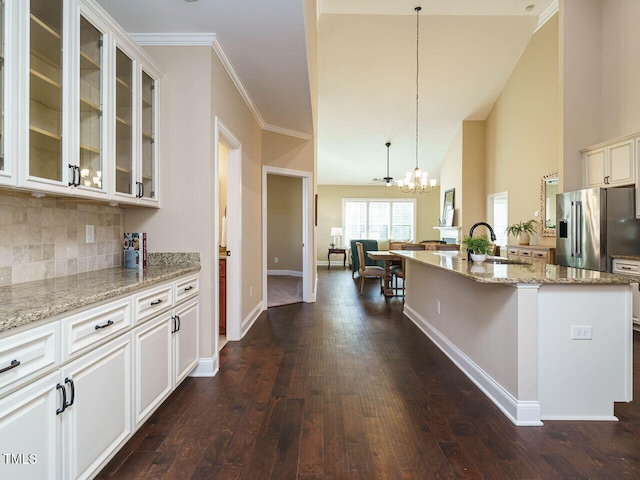 kitchen with pendant lighting, sink, white cabinetry, high quality fridge, and an island with sink