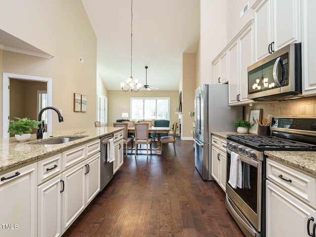 kitchen featuring sink, white cabinetry, light stone counters, decorative light fixtures, and stainless steel appliances