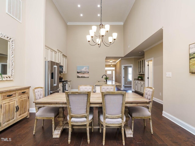 dining area with sink, ornamental molding, a notable chandelier, hardwood / wood-style floors, and a high ceiling