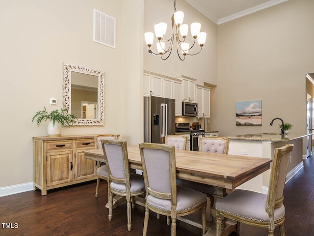 dining space with sink, crown molding, an inviting chandelier, a towering ceiling, and dark hardwood / wood-style flooring