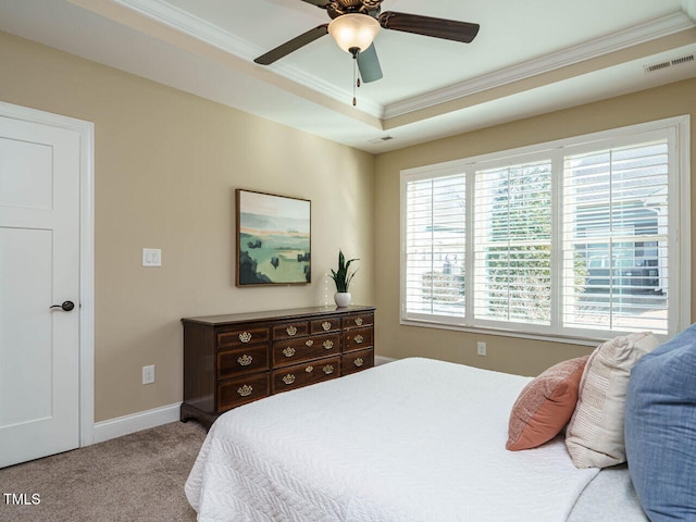 carpeted bedroom with ceiling fan, ornamental molding, and a tray ceiling