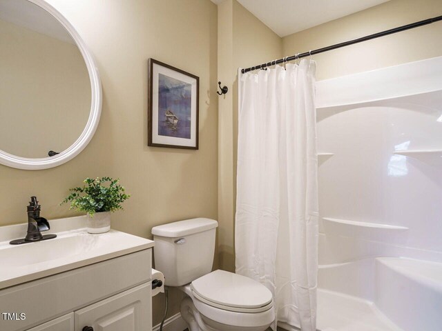 bathroom featuring walk in shower, vanity, and toilet