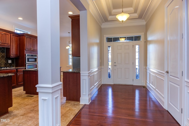 foyer featuring a wealth of natural light, ornamental molding, and wood-type flooring