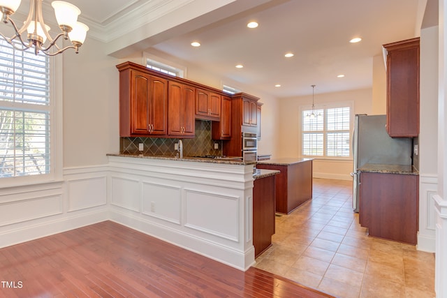 kitchen featuring tasteful backsplash, hanging light fixtures, light stone countertops, and appliances with stainless steel finishes