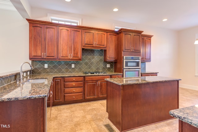 kitchen with stainless steel appliances, sink, stone counters, and decorative backsplash