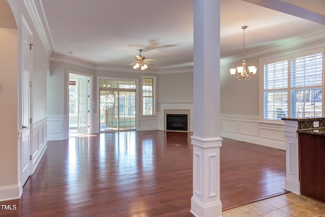 unfurnished living room with hardwood / wood-style floors, ceiling fan with notable chandelier, ornamental molding, and decorative columns