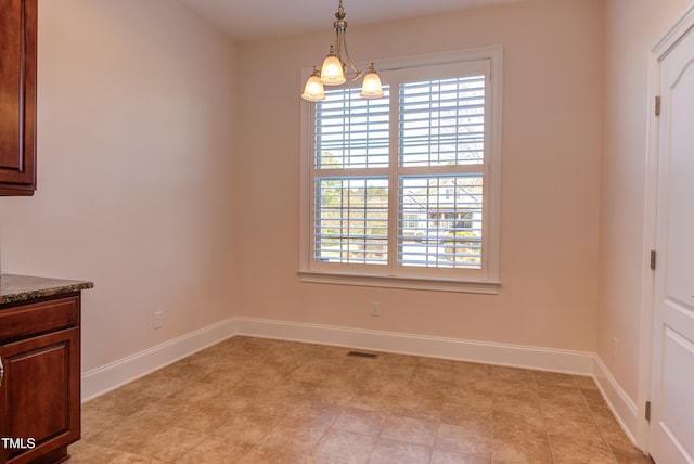 unfurnished dining area featuring a chandelier