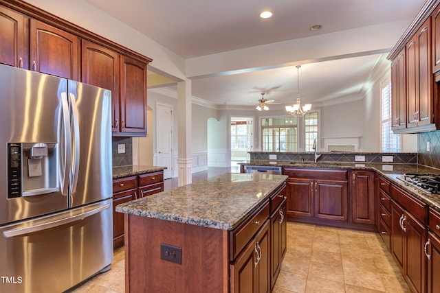 kitchen featuring pendant lighting, stainless steel appliances, a center island, and dark stone countertops