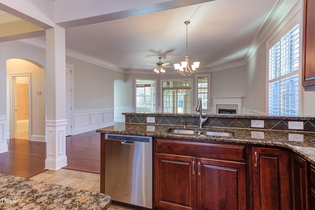 kitchen with plenty of natural light, sink, stainless steel dishwasher, and dark stone counters