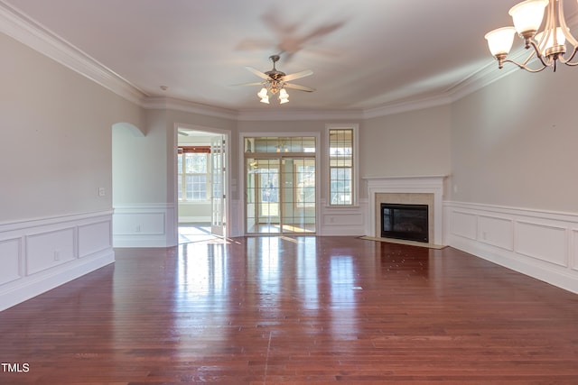 unfurnished living room featuring dark wood-type flooring, ornamental molding, and ceiling fan with notable chandelier