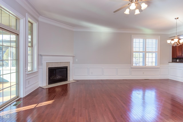 unfurnished living room featuring a tile fireplace, dark wood-type flooring, ceiling fan with notable chandelier, and ornamental molding