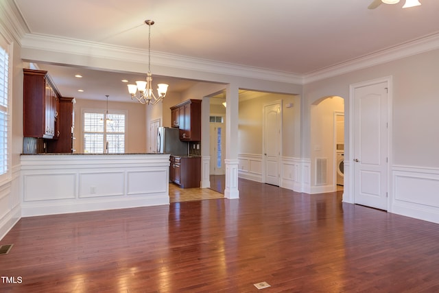 interior space with crown molding, hanging light fixtures, stainless steel fridge, dark hardwood / wood-style flooring, and kitchen peninsula