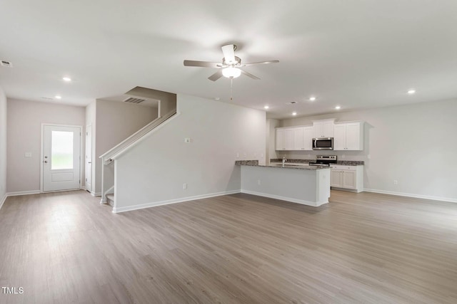 unfurnished living room with sink, ceiling fan, and light wood-type flooring