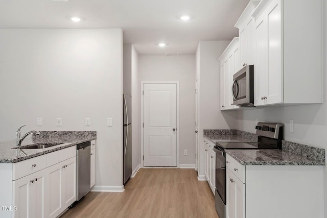 kitchen with appliances with stainless steel finishes, dark stone counters, and white cabinets