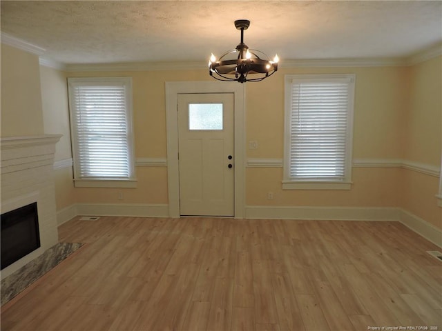 foyer featuring crown molding, a wealth of natural light, light hardwood / wood-style flooring, and a notable chandelier