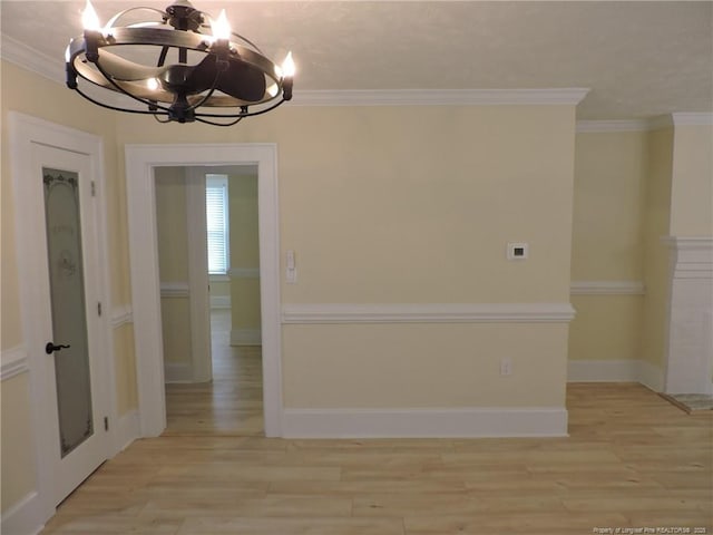 unfurnished room featuring a notable chandelier, ornamental molding, and light wood-type flooring