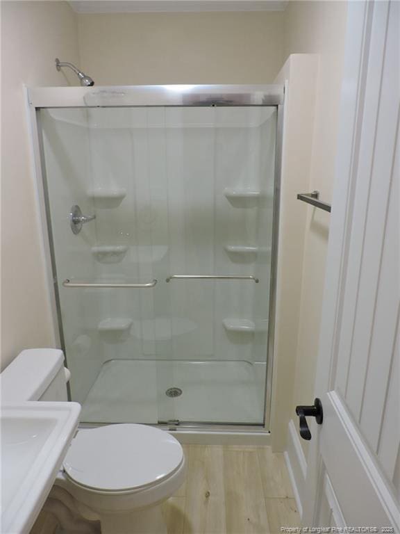 bathroom with hardwood / wood-style flooring, toilet, and a shower with shower door