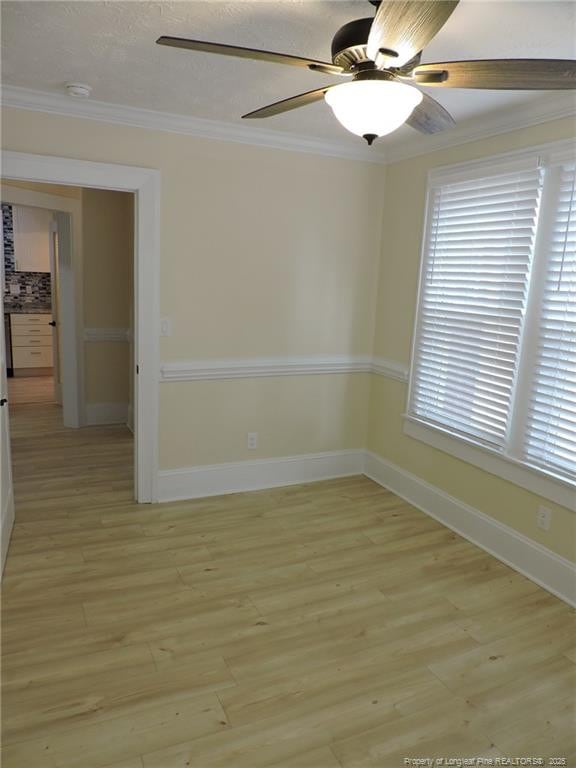 empty room with ceiling fan, ornamental molding, and light hardwood / wood-style floors