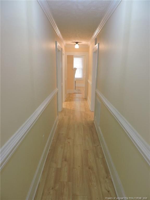 corridor with crown molding and light hardwood / wood-style flooring