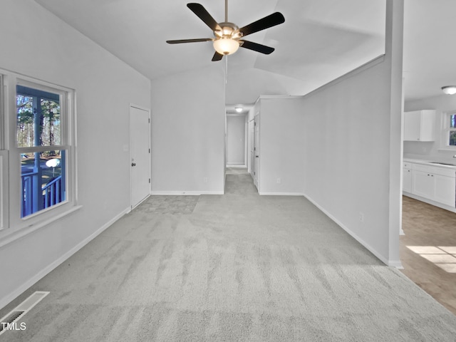 unfurnished living room with lofted ceiling, sink, light carpet, and ceiling fan