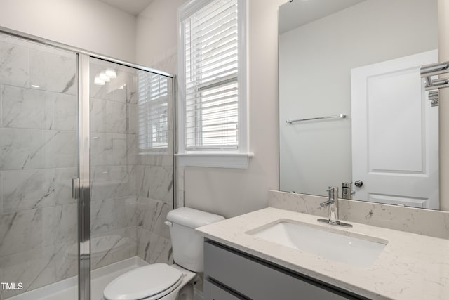 bathroom featuring a shower with door, vanity, and toilet