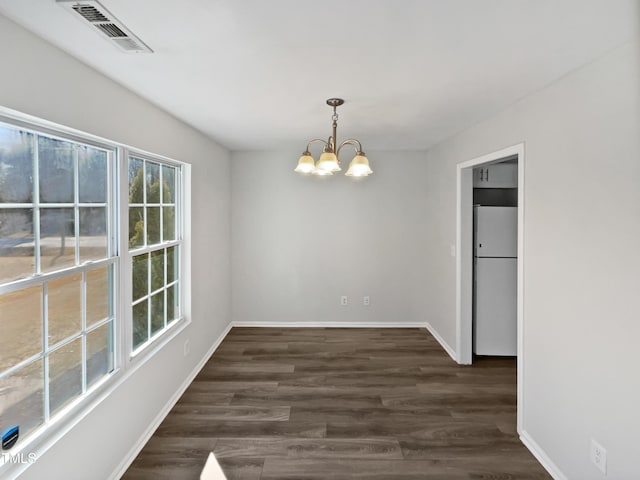 unfurnished dining area featuring an inviting chandelier and dark hardwood / wood-style floors