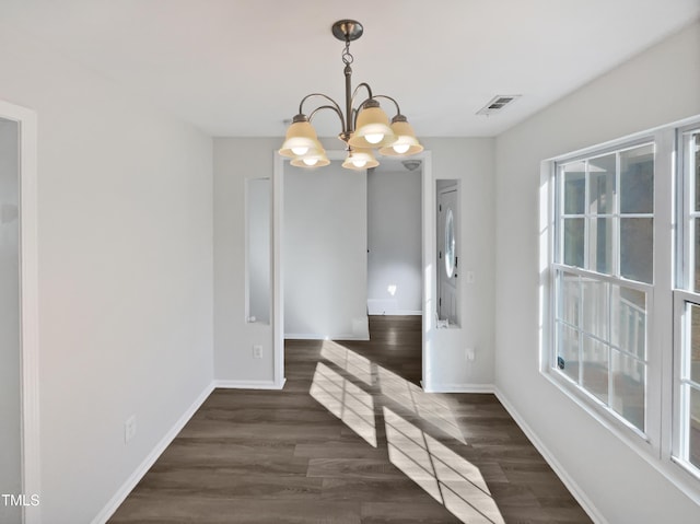 unfurnished dining area featuring dark wood-type flooring and an inviting chandelier