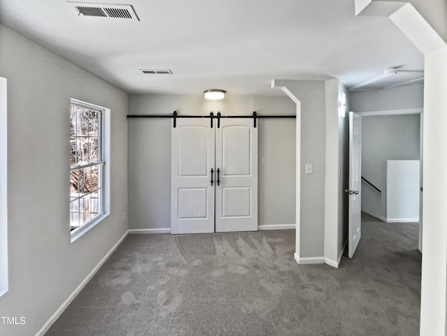 unfurnished bedroom featuring a barn door and carpet floors