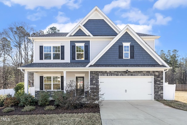 craftsman-style home with driveway, a porch, stone siding, and fence