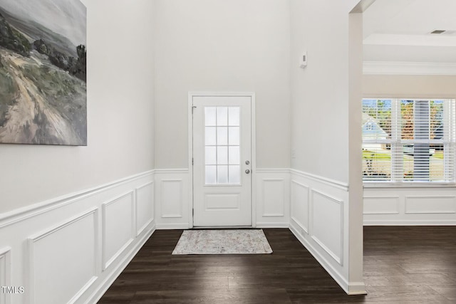 doorway with wainscoting, dark wood finished floors, crown molding, and a decorative wall