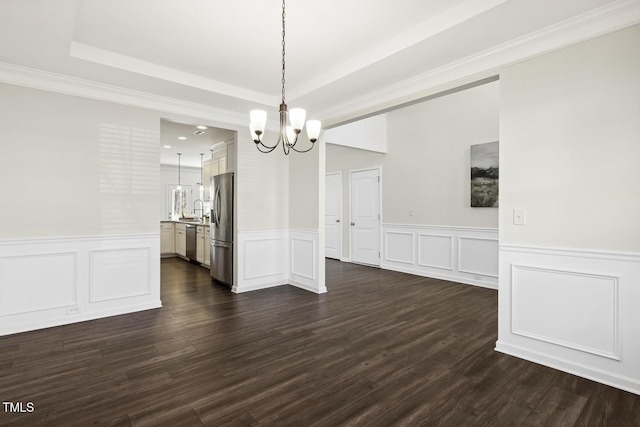 unfurnished dining area featuring a tray ceiling, dark wood-style flooring, a sink, and an inviting chandelier