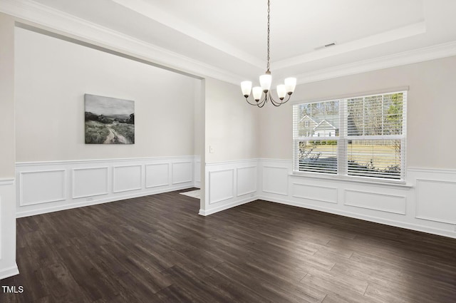 unfurnished dining area with wainscoting, a raised ceiling, dark wood finished floors, and an inviting chandelier