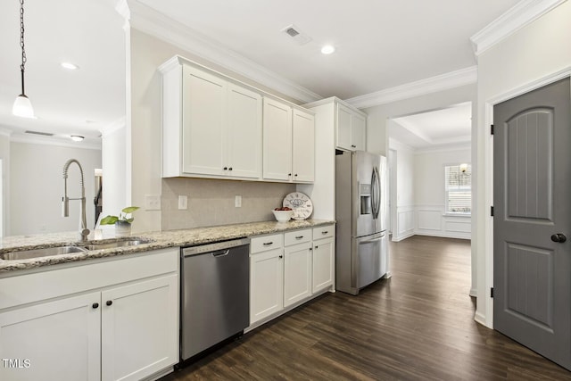 kitchen with light stone counters, pendant lighting, appliances with stainless steel finishes, white cabinetry, and a sink