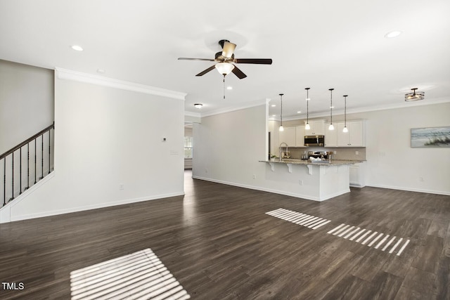 unfurnished living room featuring dark wood-style flooring, crown molding, baseboards, and ceiling fan