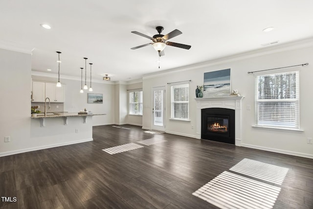 unfurnished living room featuring a glass covered fireplace, dark wood finished floors, visible vents, and crown molding