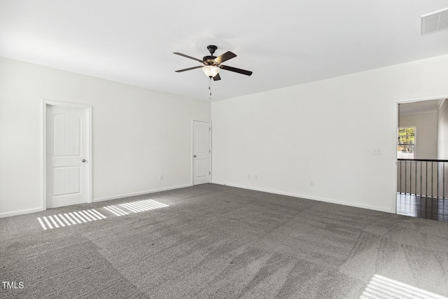 spare room featuring visible vents, dark carpet, baseboards, and ceiling fan