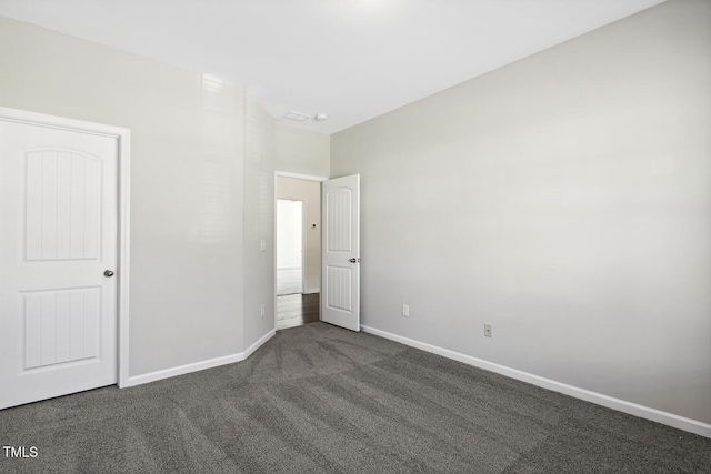 unfurnished bedroom featuring dark colored carpet and baseboards