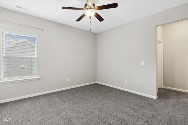 unfurnished room featuring visible vents, dark carpet, baseboards, and ceiling fan